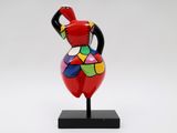 a colorful vase on a black stand on a white background