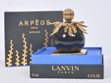 une image représentant un flacon de parfum noir et doré posé sur une boîte bleue