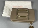 beige wallet with a gold ring on it and a white bag