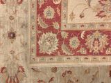 a close up of a red and beige rug with a bird on it