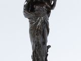 une vieille statue en bronze représentant une femme avec un panier sur la tête