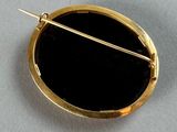 an image of a gold and black broochle with a pin in it