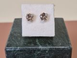 a pair of diamond stud earrings sitting on top of a marble block