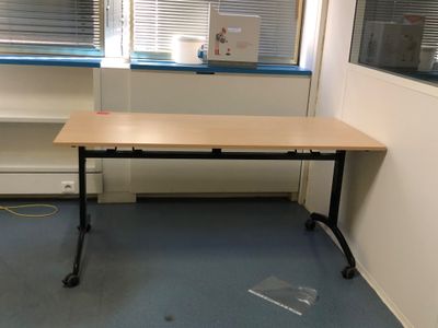 un bureau dans un coin d'une pièce, avec une fenêtre en arrière-plan