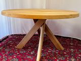 a wooden table with three wooden legs on a red carpet