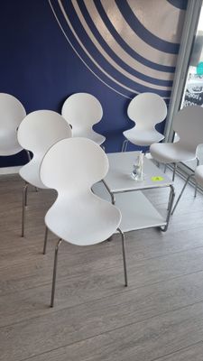 plusieurs chaises blanches et une table dans une pièce aux murs bleus