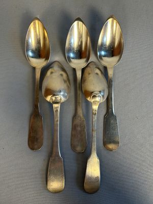 four silver spoons and two silver spoons on a gray surface