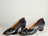 a pair of black leather shoes with a gold bow on the heel