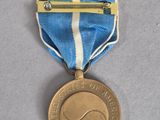 an image of a gold medal with a blue ribbon on a gray surface