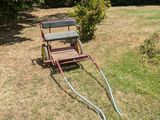un petit chariot muni d'un tuyau, posé dans l'herbe