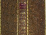 an old book with a red cover sitting on top of a white table