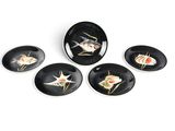 quatre assiettes noires ornées de motifs de poissons, posées sur une surface blanche