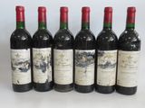 six bottles of wine are lined up in a row on a white surface