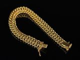 a close up of a gold chain bracelet on a black background