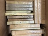 many books stacked in a cardboard box on top of each other