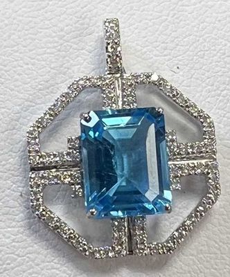 un gros plan d'un pendentif en pierre bleue et diamants posé sur une surface blanche