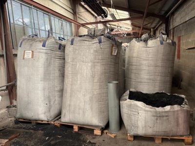des sacs de charbon de bois posés sur des palettes devant un bâtiment
