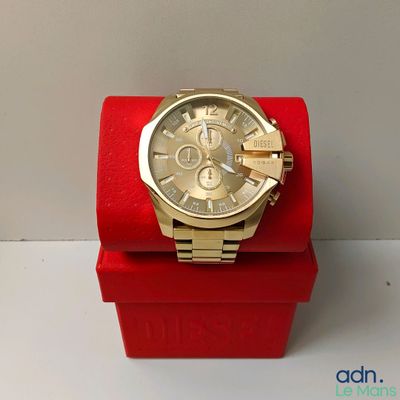 a gold watch on a red box on a white surface