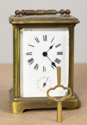 une petite horloge en laiton avec une clé, posée sur une table