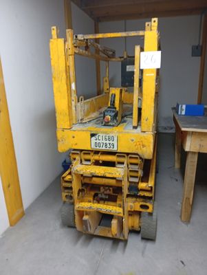 a yellow forklift sitting in a room with a table and chairs