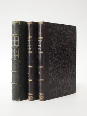 two old books sitting on top of each other on a white surface