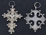 two silver cross pendants on a black background