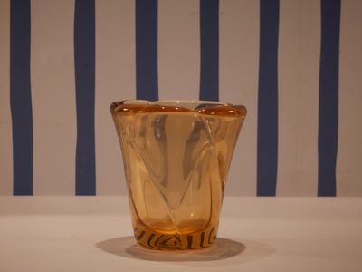 a glass vase sitting on a table with a striped wall behind it