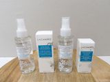 three bottles of skin care sitting on top of a wooden table