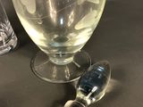 two glasses and a vase on a table next to each other
