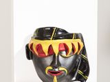 un masque noir et jaune exposé sur une étagère blanche