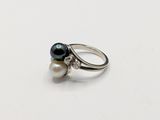 a close up of a ring on a white surface with two pearls