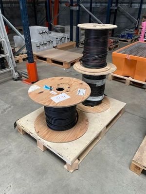 Deux bobines de fils noirs se trouvent sur des palettes dans un entrepôt