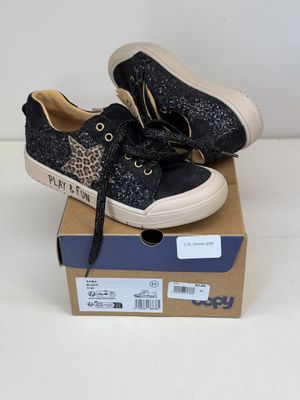 des baskets noires et blanches ornées d'un imprimé léopard, posées sur une boîte