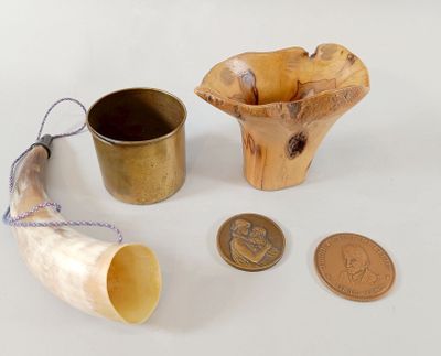 a small horn, a cup, and a coin on a table
