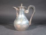 a silver coffee pot with a handle on a table