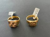 two gold rings on a black surface with tags on them