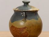 a brown and blue jar with a lid on a table
