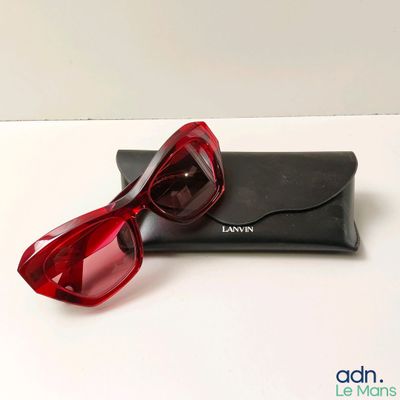 des lunettes de soleil rouges posées sur un étui noir, sur une surface blanche