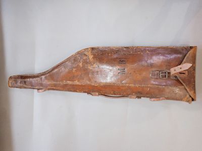 un vieil étui en cuir muni d'une poignée en bois, posé sur une surface blanche