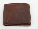 un portefeuille en cuir marron posé sur une surface blanche