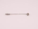 a silver pin with a flower on it sitting on a white surface