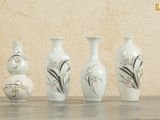 quatre vases posés sur une table, avec un mur en arrière-plan