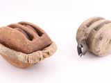 deux objets en bois posés sur une surface blanche : l'un est une poulie et l'autre est une poulie