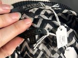 someone is holding a black and white bag with a tag on it