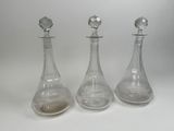 three clear glass decanters sitting next to each other on a white surface