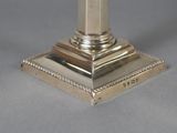 an antique silver plated candle holder on a grey background