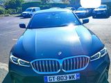 une BMW noire garée sur un parking, avec une plaque d'immatriculation