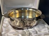 a silver bowl sitting in a box on a white cloth