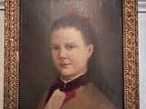 portrait d'une femme vêtue d'un manteau marron et d'un nœud papillon rouge