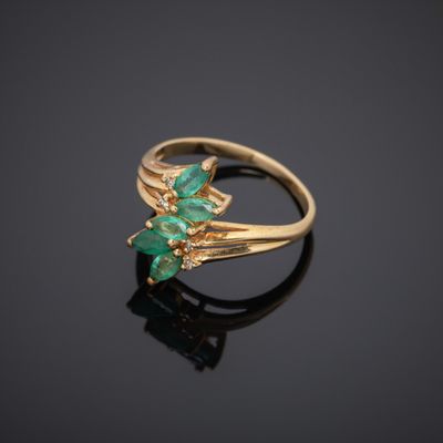 a gold ring with emerald stones on a black surface